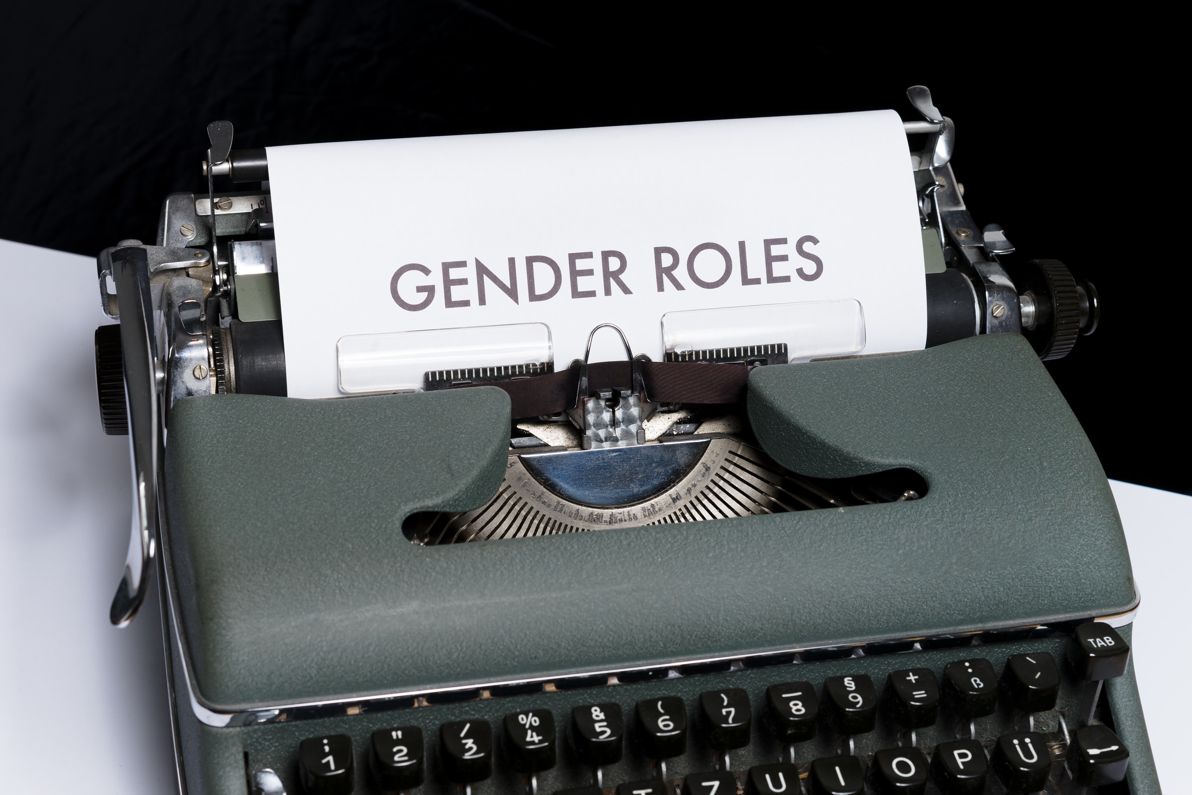 A black typewriter showing a white paper with GENDER ROLES writter in it