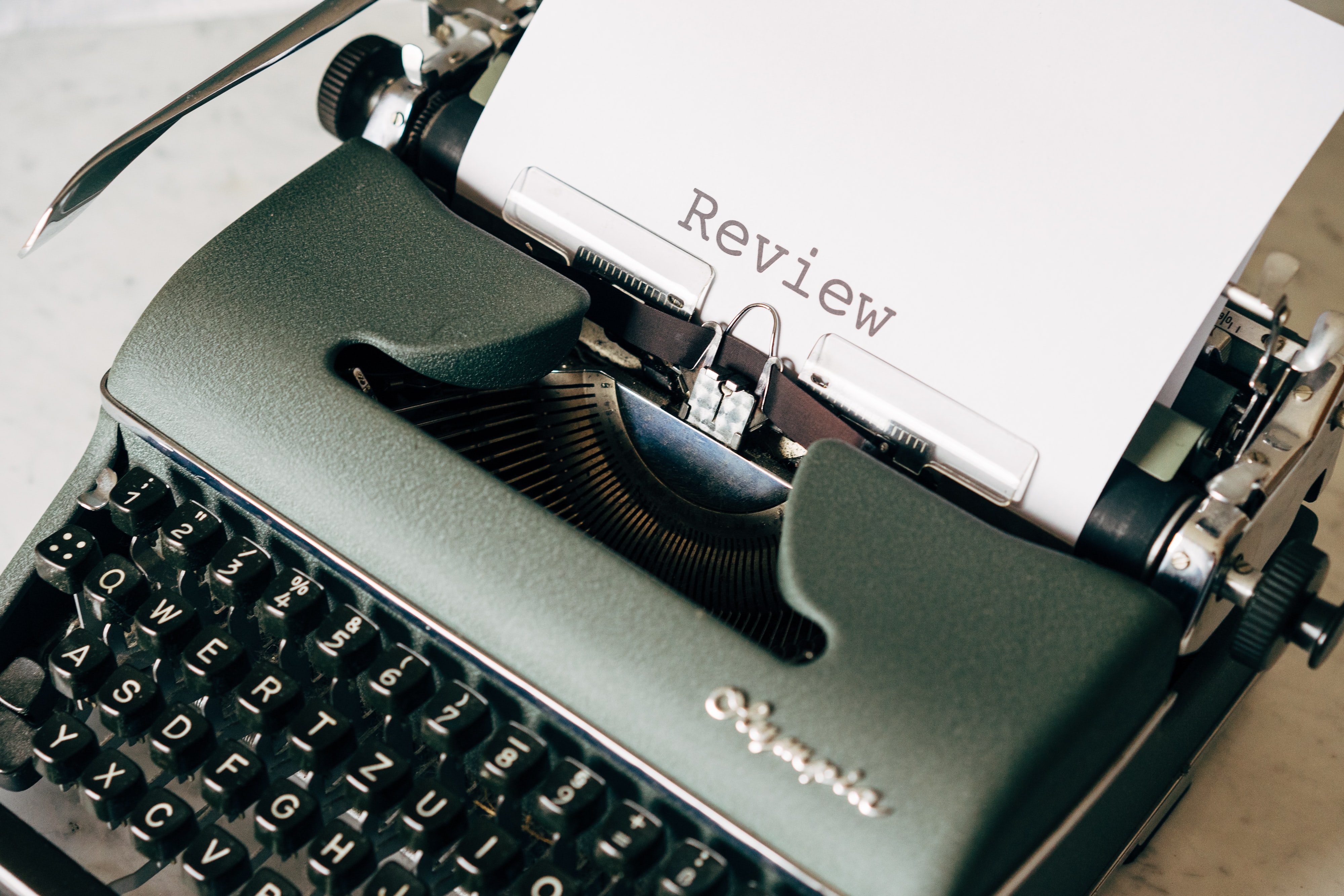 A book review being created on a pretty black typewriter.