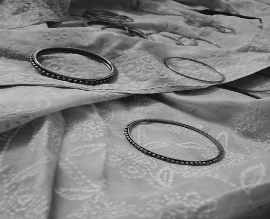 Beautiful bangles lying scattered recklessly on a pretty piece of cloth used as a stole.