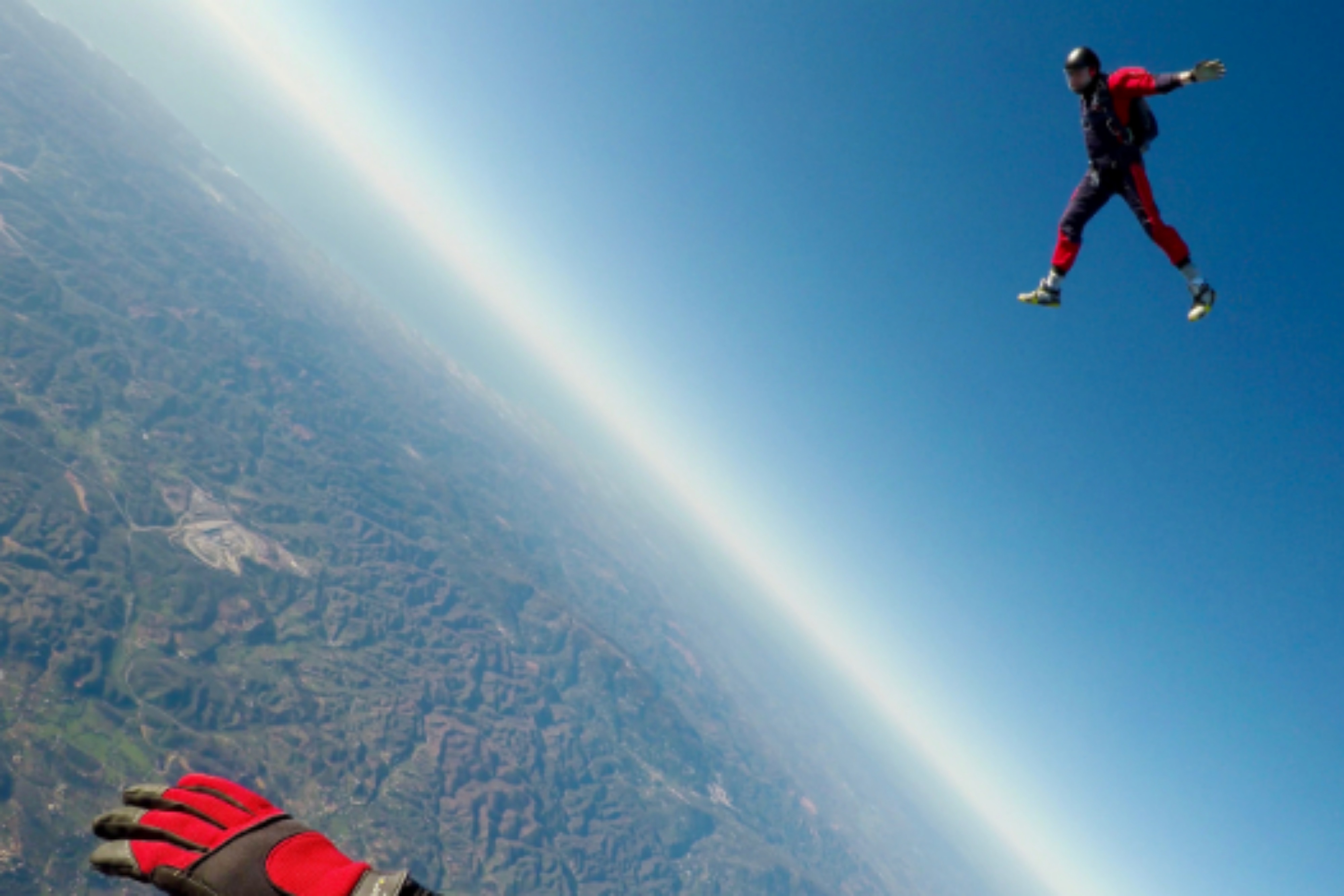 Two friends enjoying sky diving at unimaginable height in the perfect blue sky.
